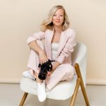 Business Fotografin mit professioneller Kamera in Fotostudio sitzend auf Sessel